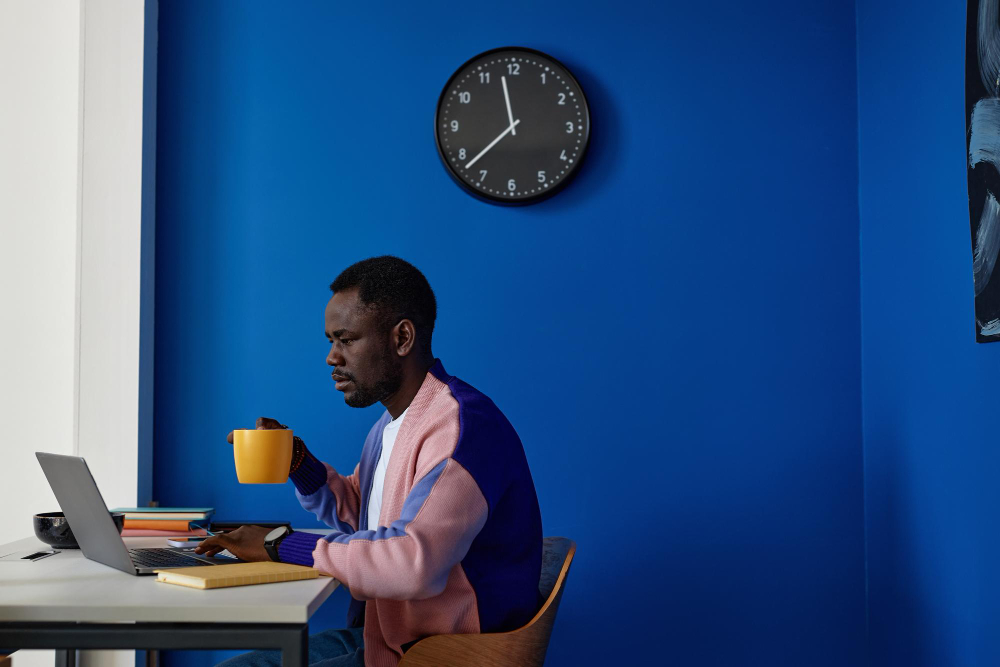 A Tranarc engineer working at a laptop with a cup of coffee in a blue office